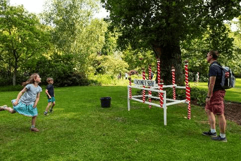 Children playing coconut shy game in a lush green park