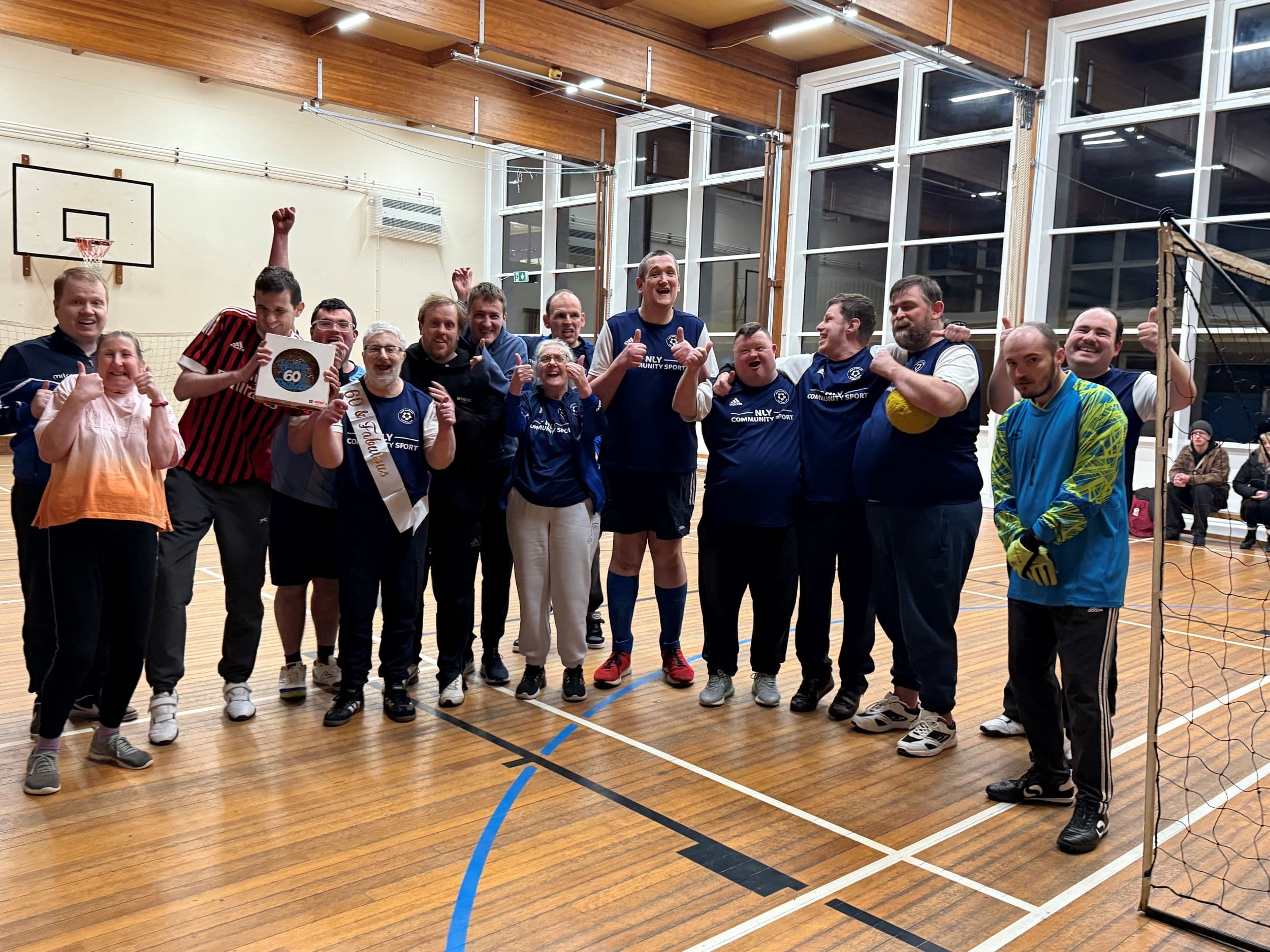Group of people celebrating in a sports hall with a volleyball net