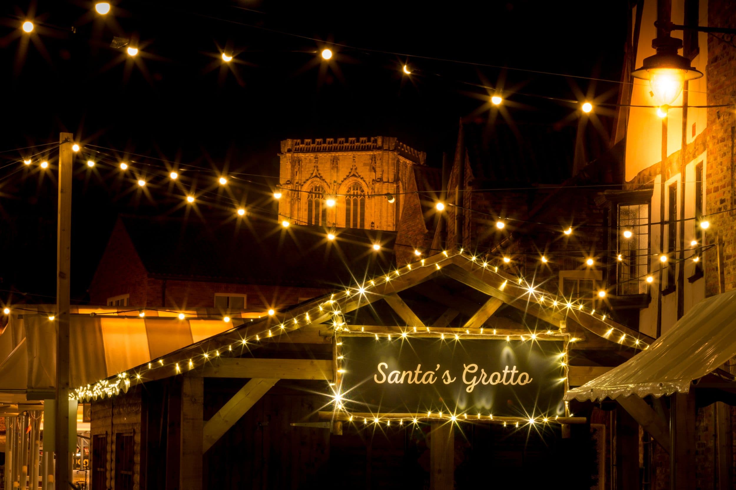 Festive market with Santa's Grotto and string lights at night