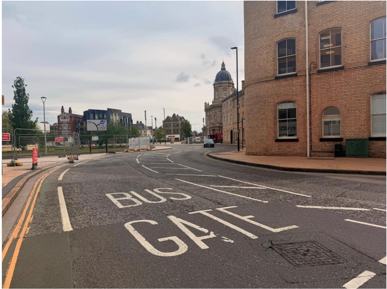 Curved city street with historic buildings and bus gate