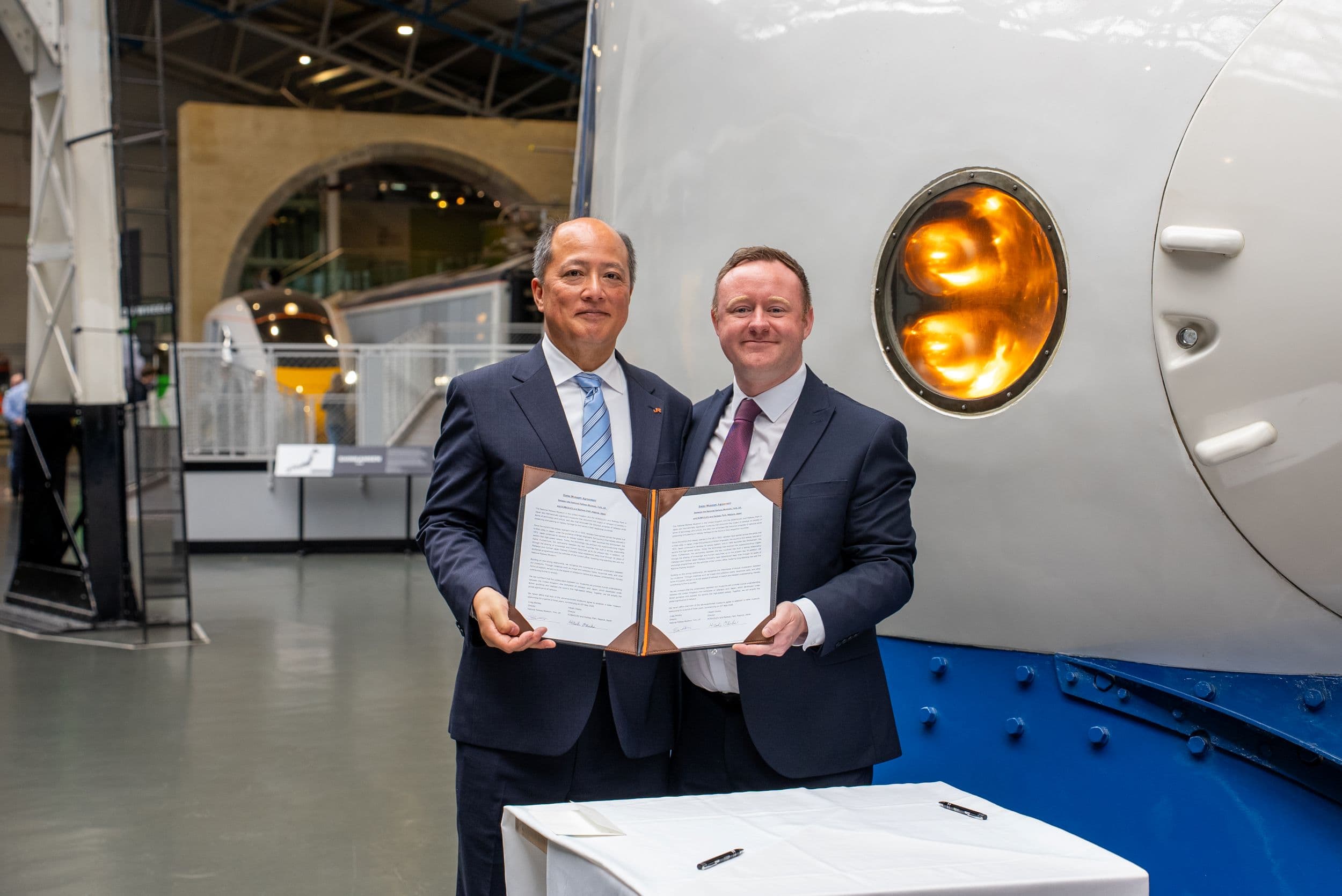 Two men holding a signed document at a railway museum