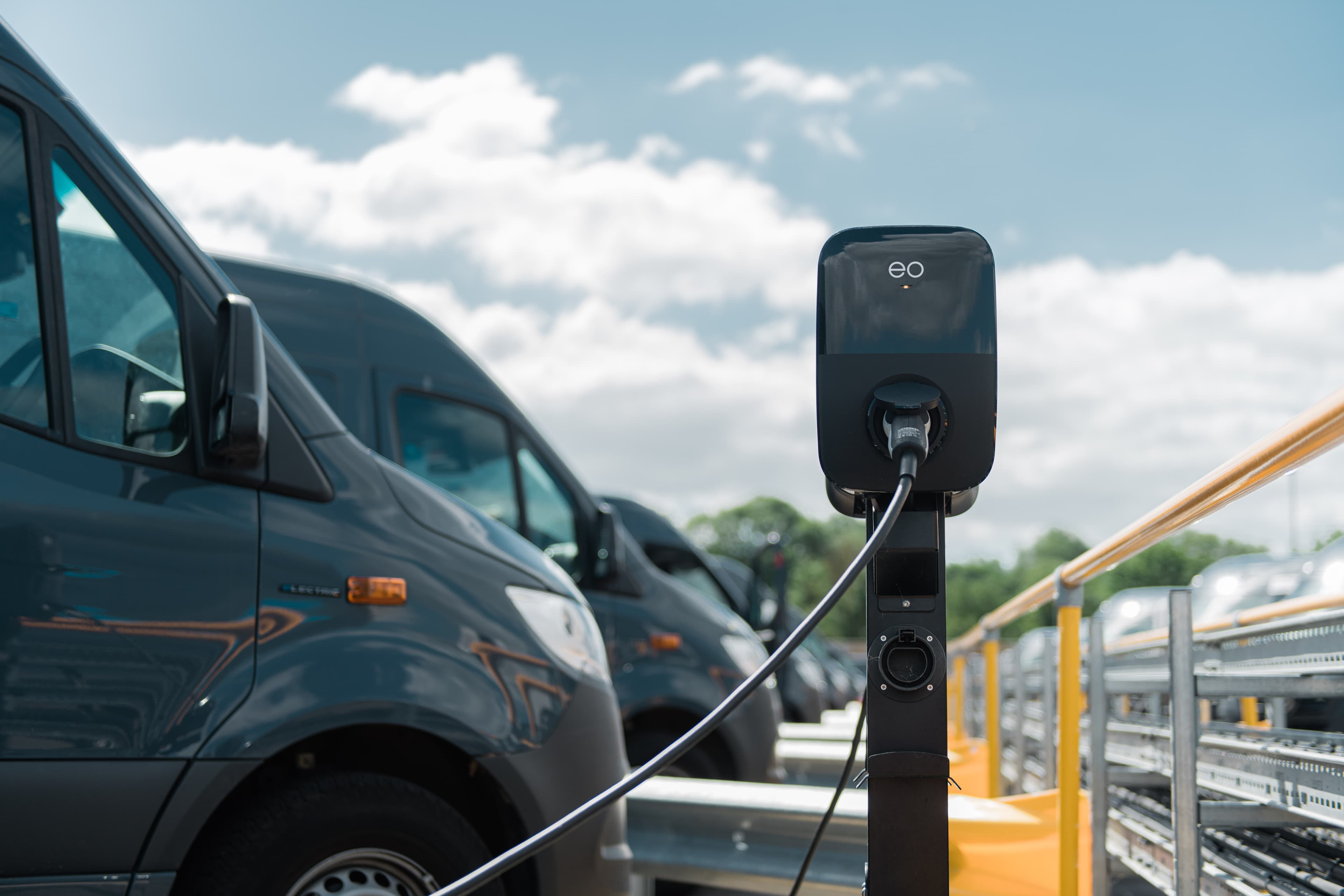 Electric vehicle charging station with vans under blue sky