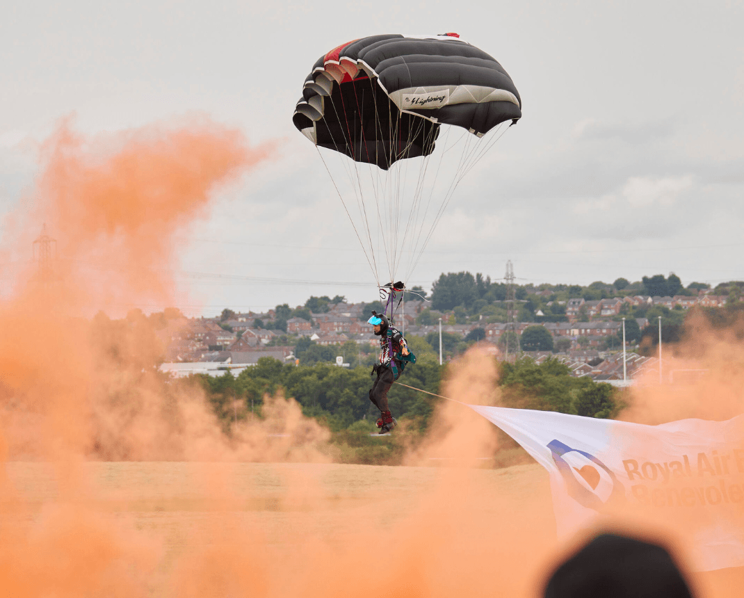 Parachutist landing with orange smoke over Yorkshire town