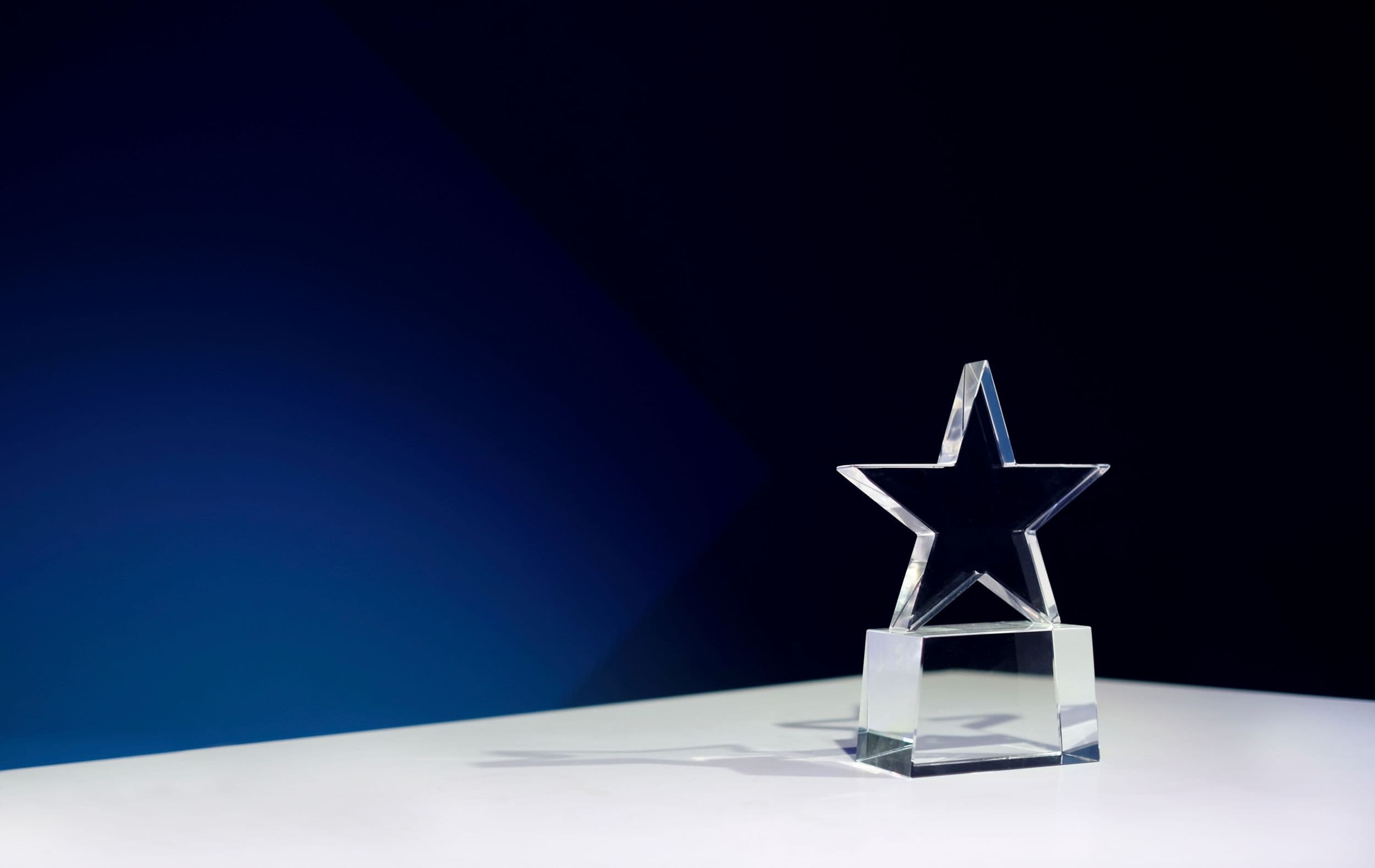 Glass star-shaped trophy on a white surface against dark background