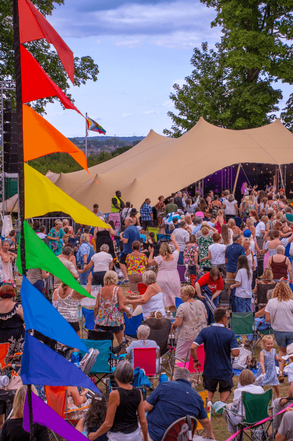 Crowd enjoying outdoor festival with colorful flags and tent
