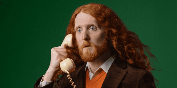 Person with long red hair holding vintage telephone