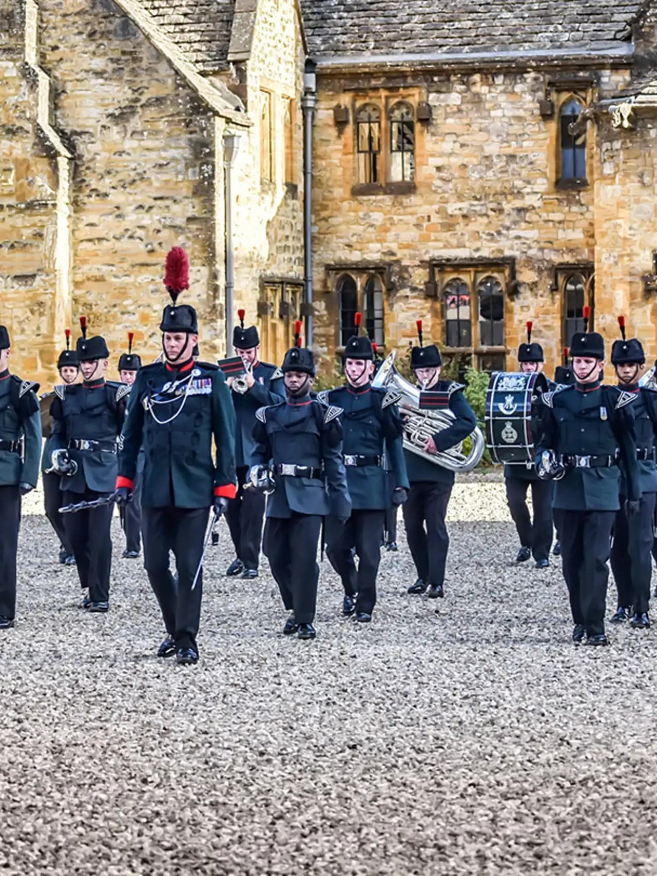 Marching band in uniform outside historic stone building