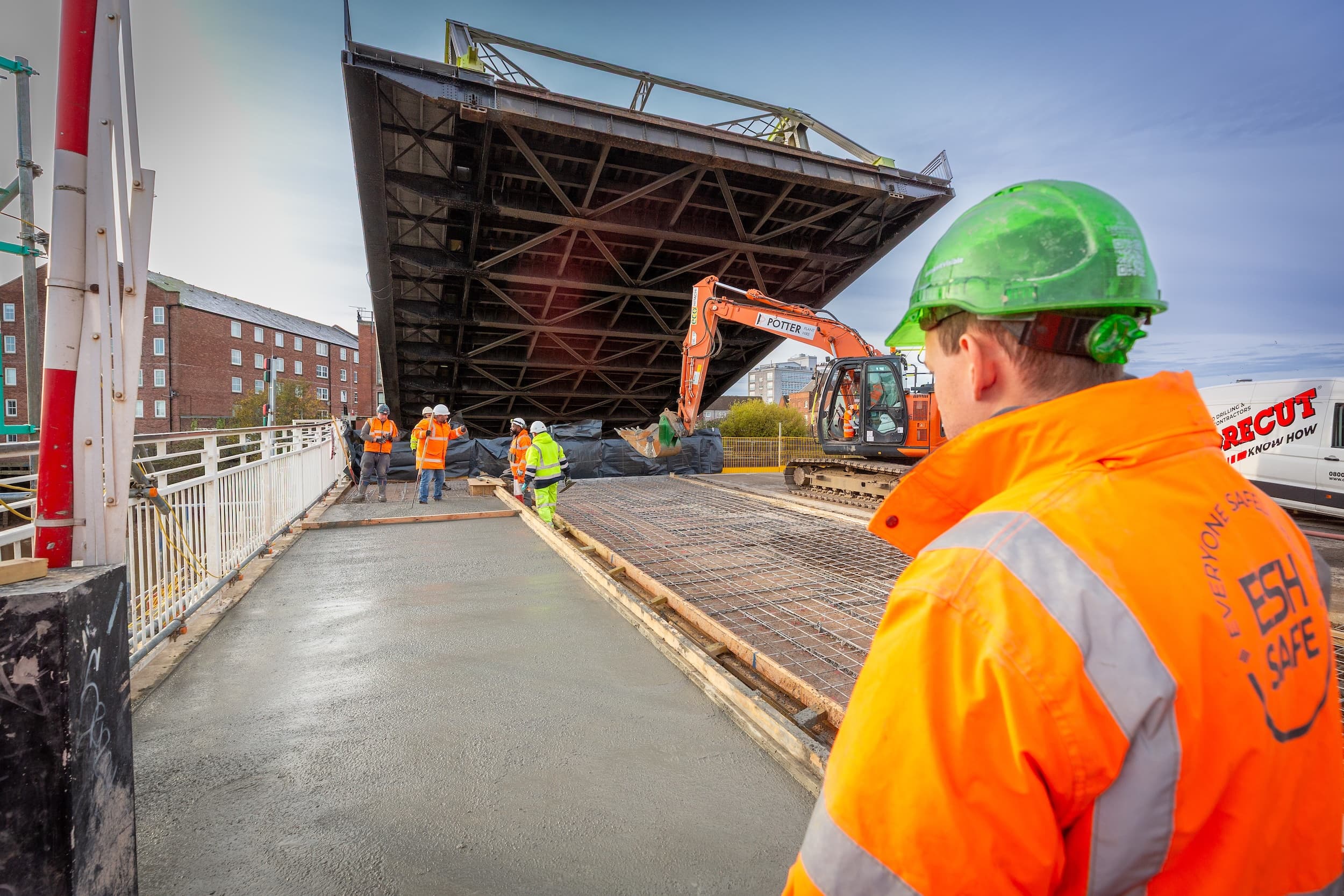 Construction workers in orange gear at a raised drawbridge