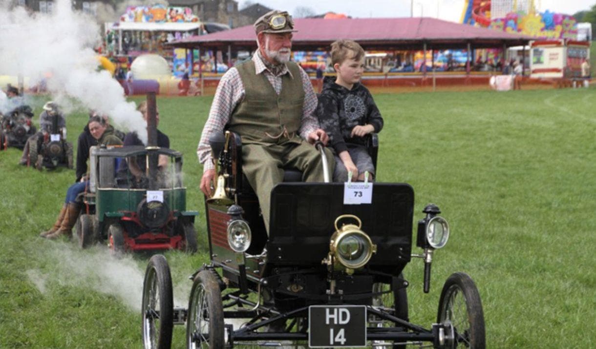 Steam-powered vintage cars parading at a Yorkshire fair