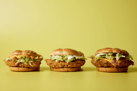 Three chicken sandwiches with lettuce on a yellow background