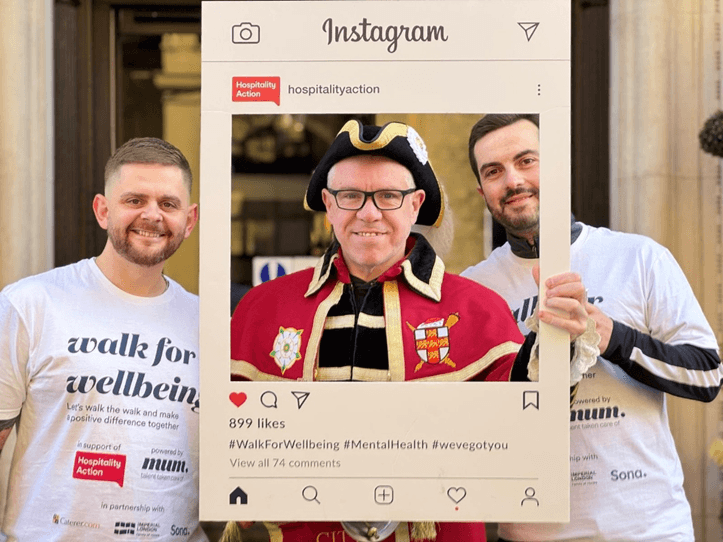 Three men posing with an Instagram frame, one in traditional attire