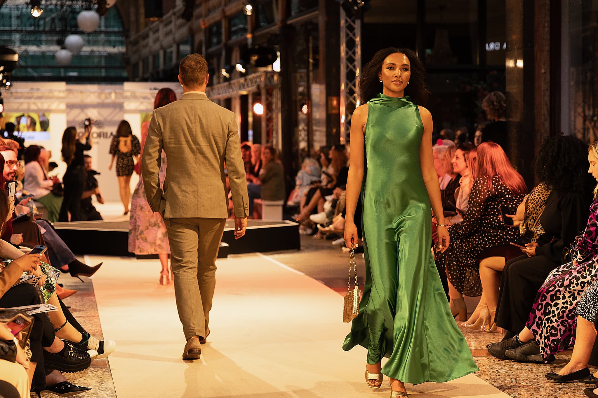 Fashion show with models on runway in vibrant shopping arcade