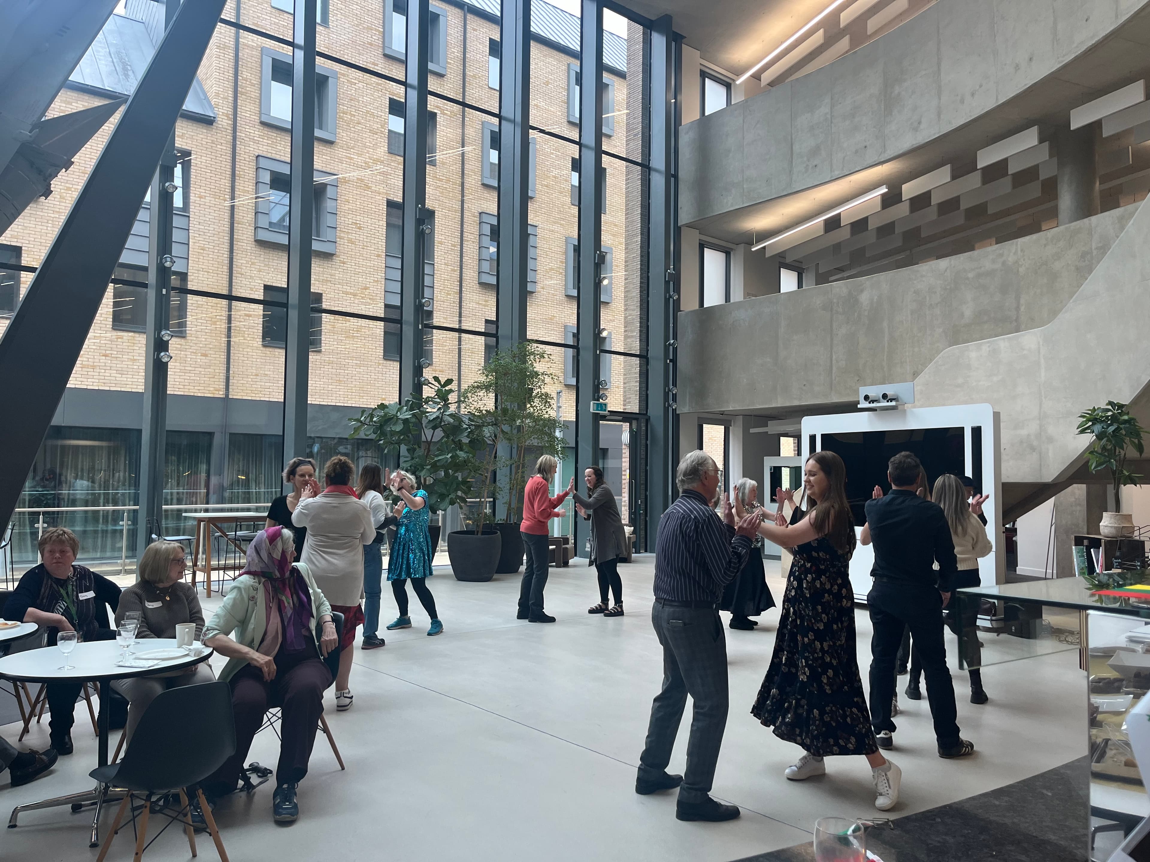 People dancing and socializing in modern atrium with large windows