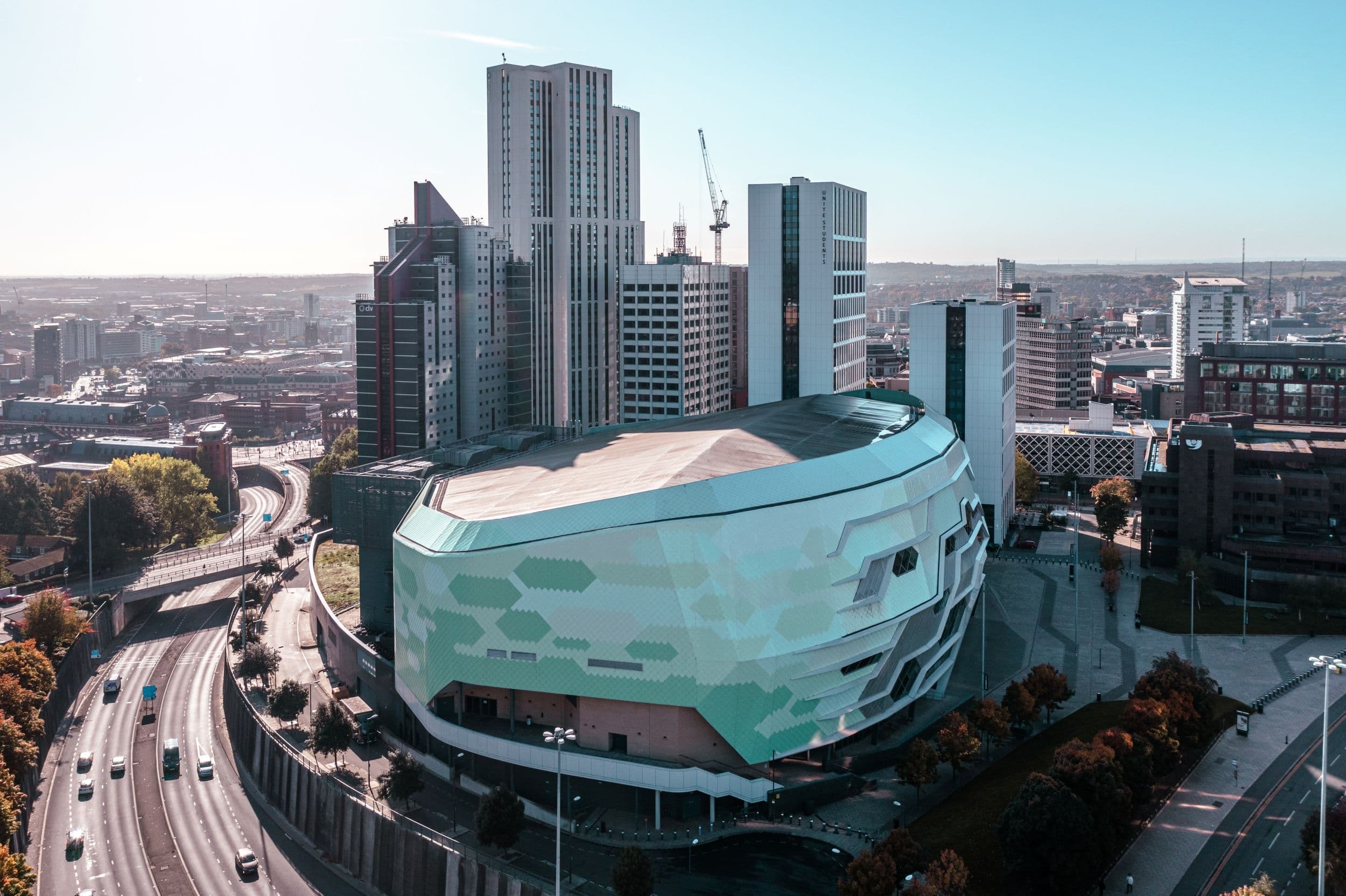Modern arena with geometric facade surrounded by tall buildings