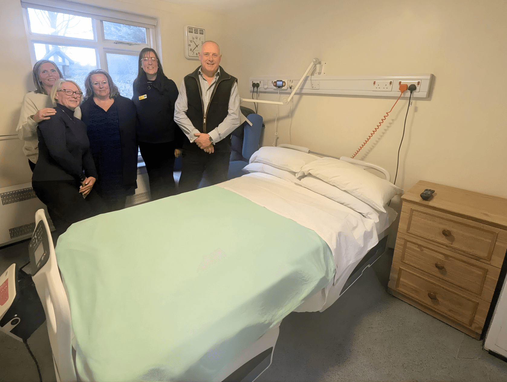 Group of five people standing in a cozy hospital room