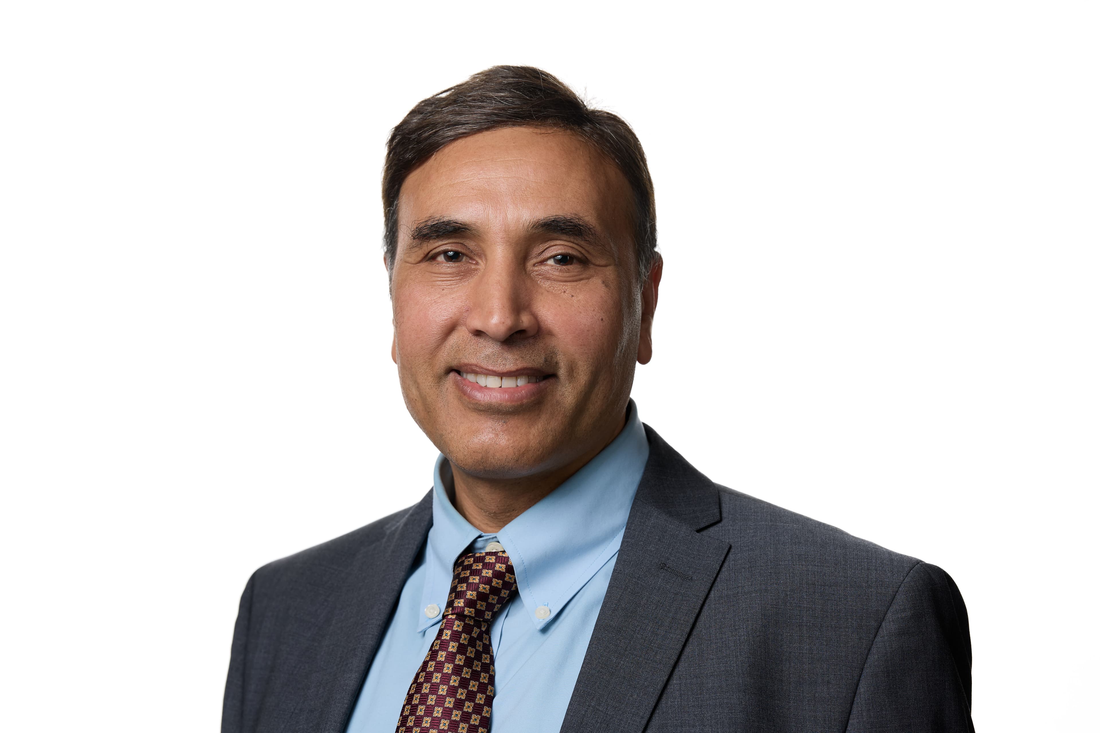 Person in a suit with a light blue shirt and patterned tie