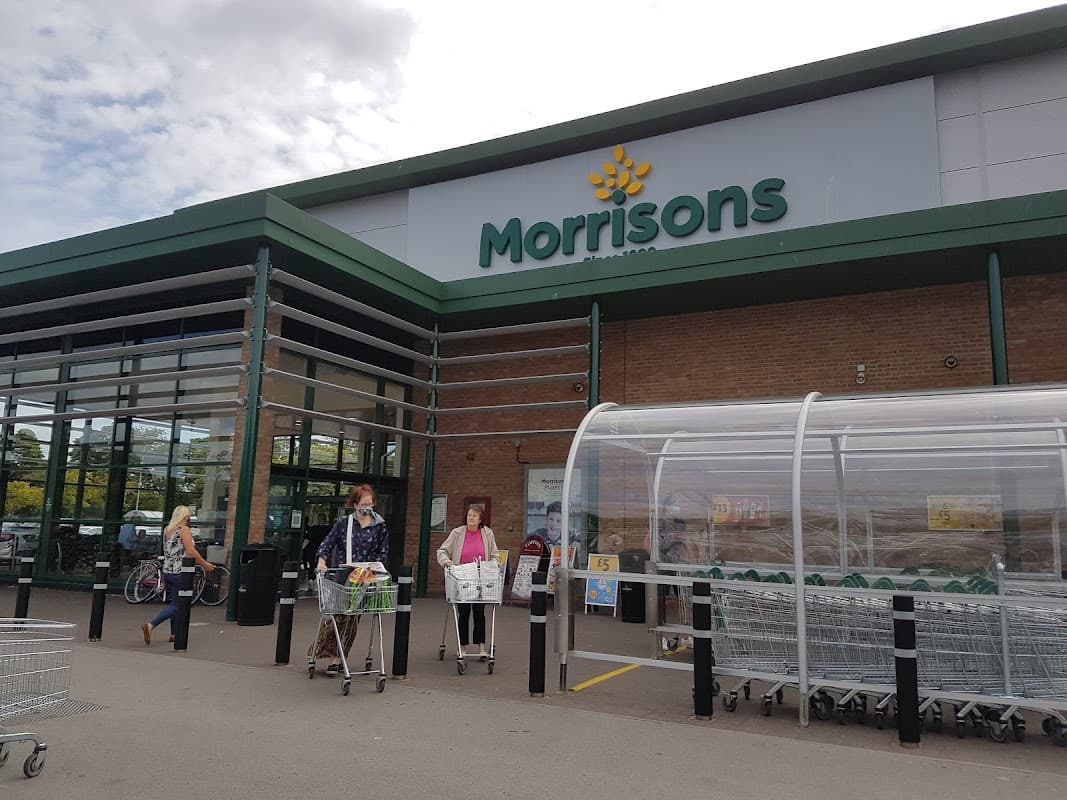 Morrisons storefront in Bessingby, Yorkshire, with shoppers and shopping carts outside.