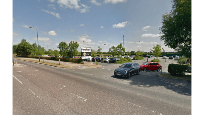 Pay & Display parking area in Earswick, Yorkshire, with multiple cars and greenery under a clear blue sky.