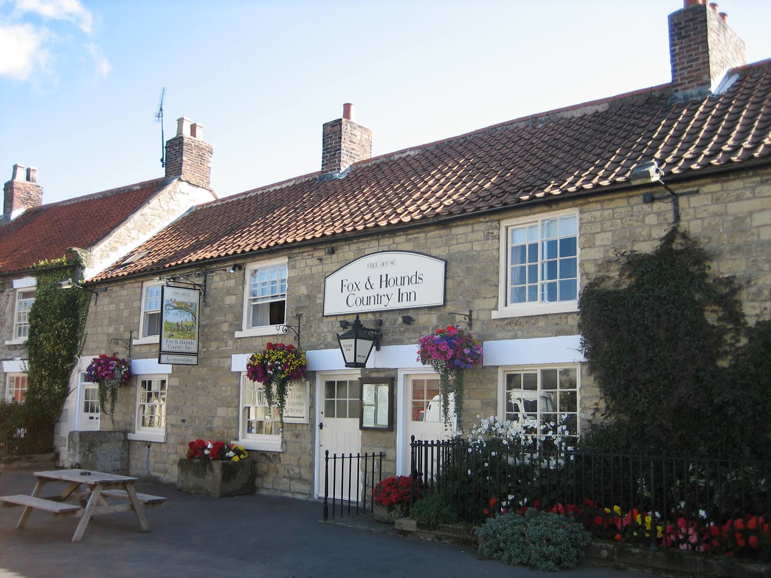 Charming stone country inn with flower baskets, ivy-covered walls, and a traditional red-tiled roof.