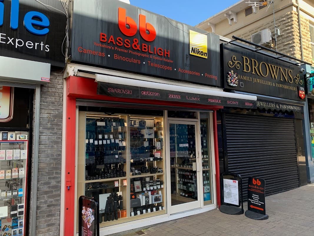 Storefront of Bass and Bligh, featuring cameras, binoculars, and telescopes, with prominent signage and display windows.