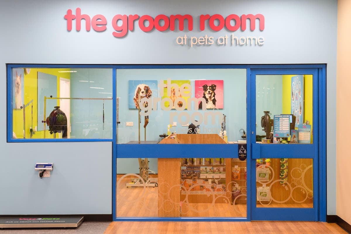 Brightly colored storefront of The Groom Room, featuring a large sign and glass doors with pet grooming equipment visible inside.