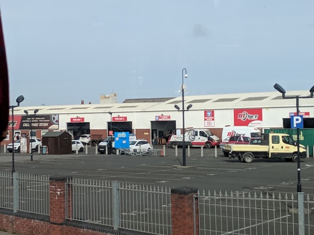 Car park with various vehicles, including vans and cars, along with signage and a fence in Hull, Yorkshire.