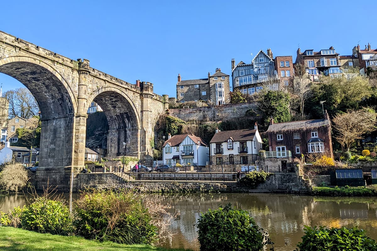 Historic stone viaduct over a scenic river with charming houses on the hillside