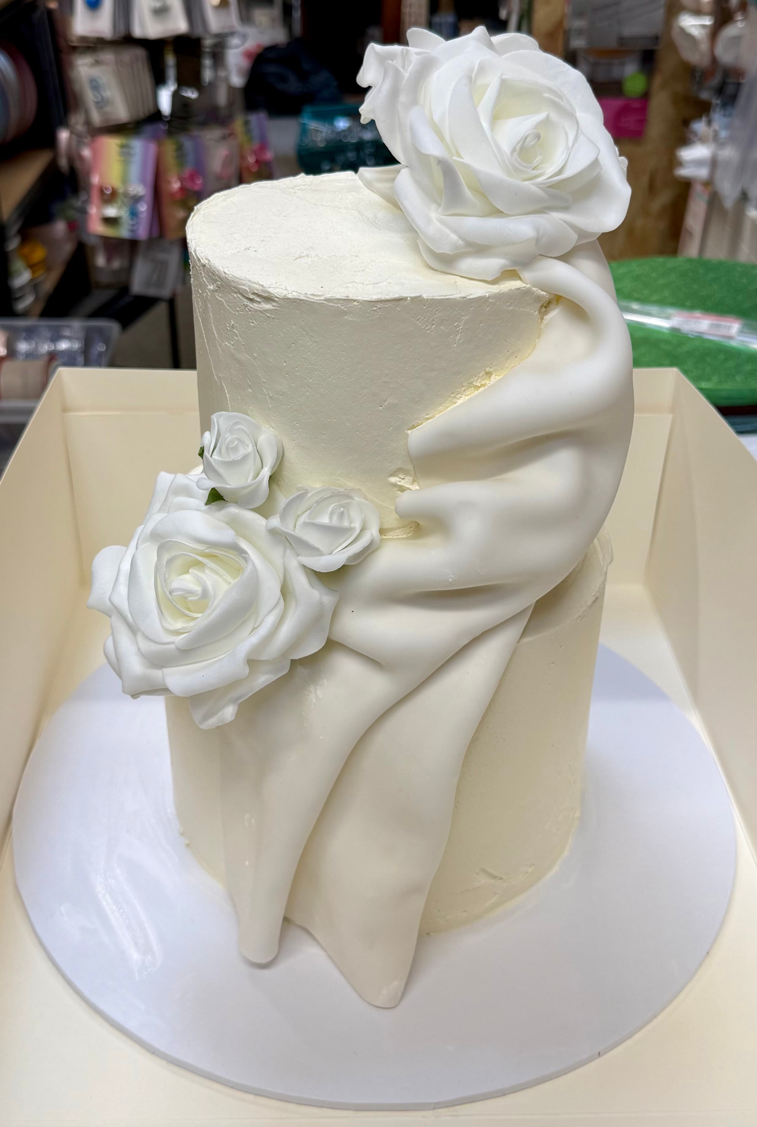 Elegant two-tier cake with white roses and draped fondant