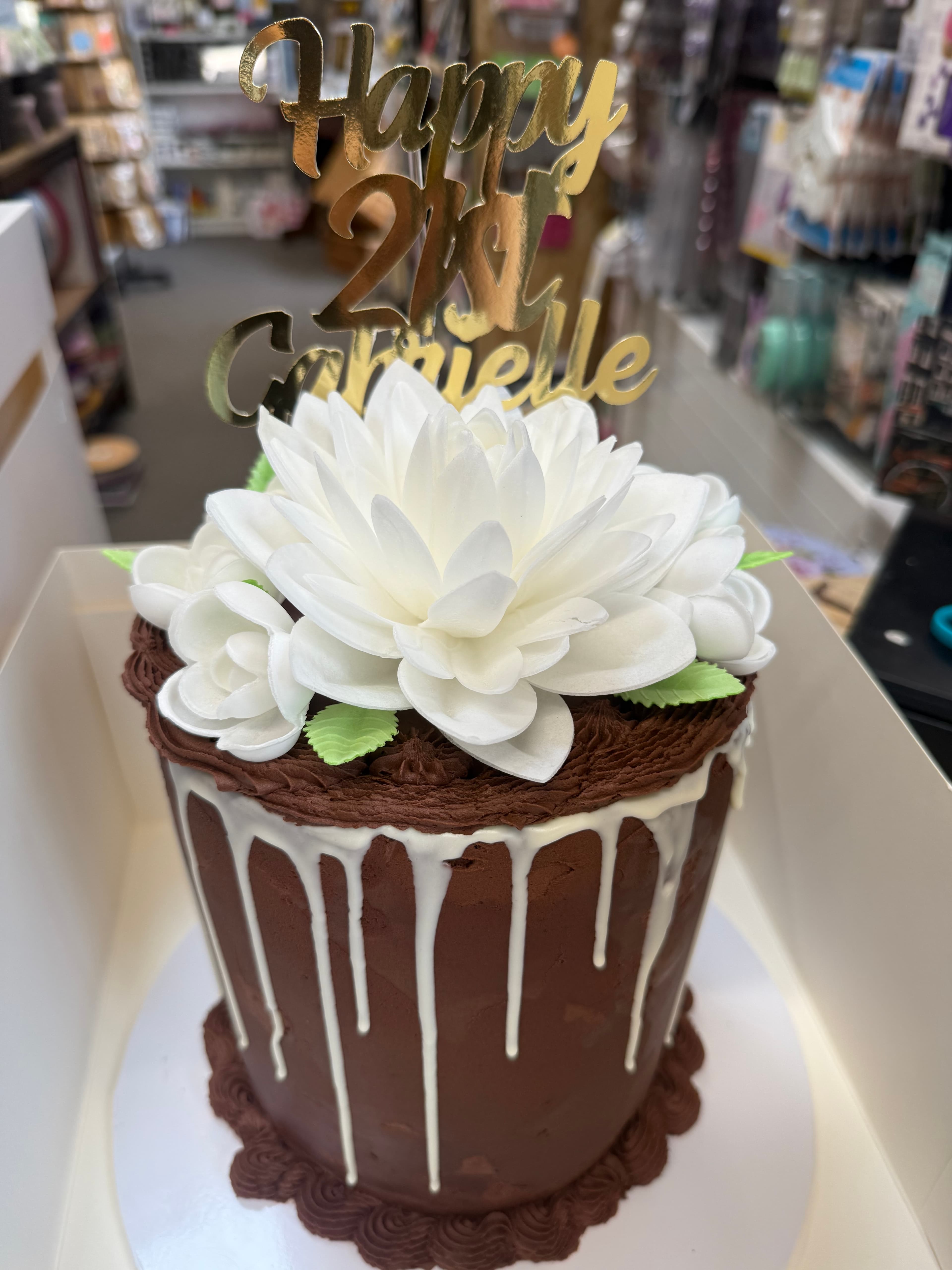 Chocolate cake with white flower decoration and gold 'Happy 21st' topper