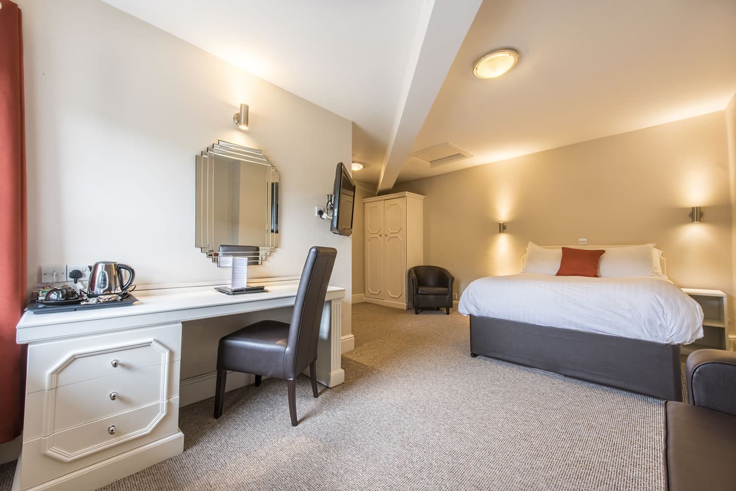 Elegant hotel room in the Imperial Crown Hotel, Halifax, featuring a cozy bed, desk, armchair, and modern lighting.