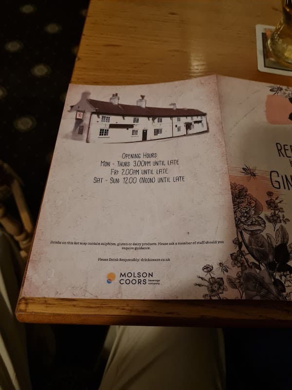 The Red Lion bar menu featuring opening hours and a cozy pub interior with wooden furniture.