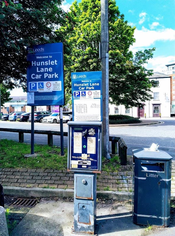 Welcome sign for Hunslet Lane Car Park, parking payment machine, litter bin, and trees in the background.