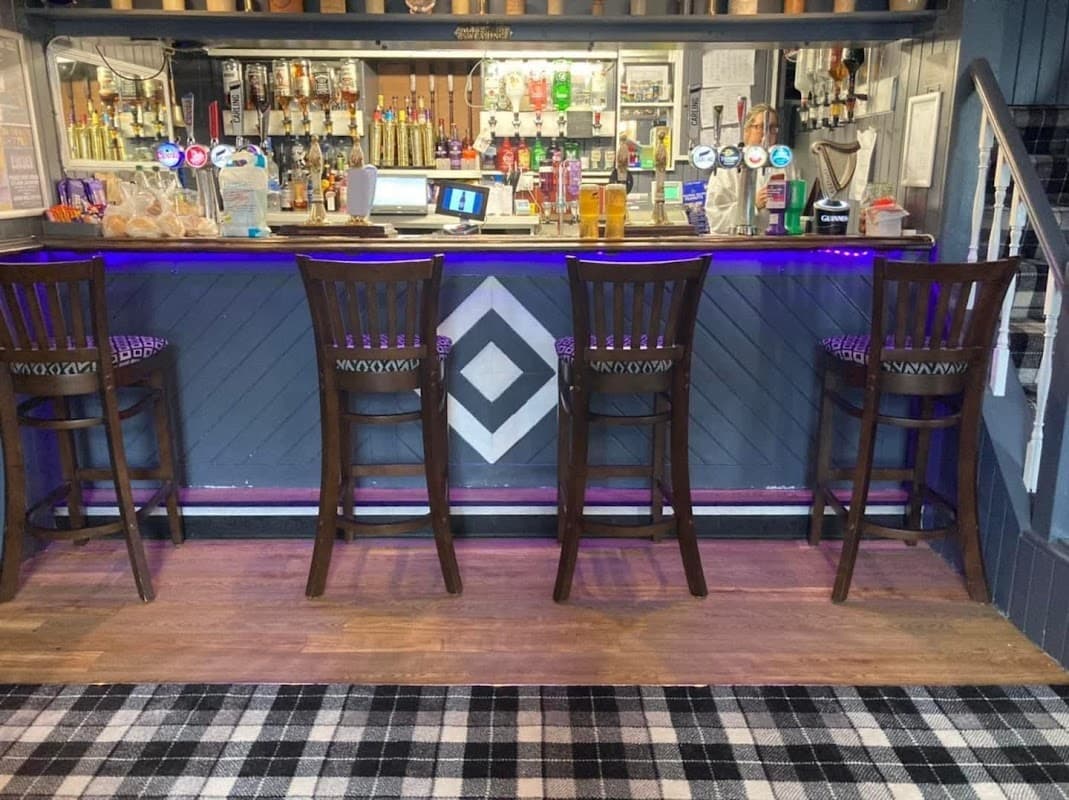 Bar area with high wooden stools, colorful beer taps, and a patterned floor in Lonsdale Hotel, Liversedge.