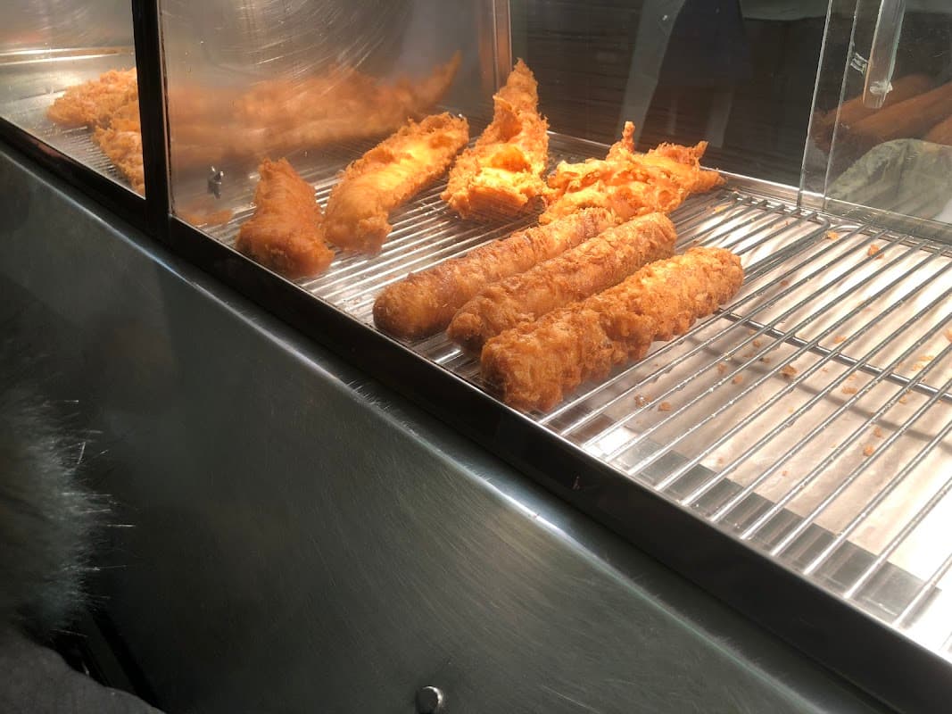 Golden-brown fish fillets and crispy batter in a display case at Oakworth Hall Fisheries.