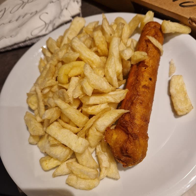 Plate of golden, crispy chips with a single battered fish fillet, served at Fish & Chippery in Skipsea, Yorkshire.