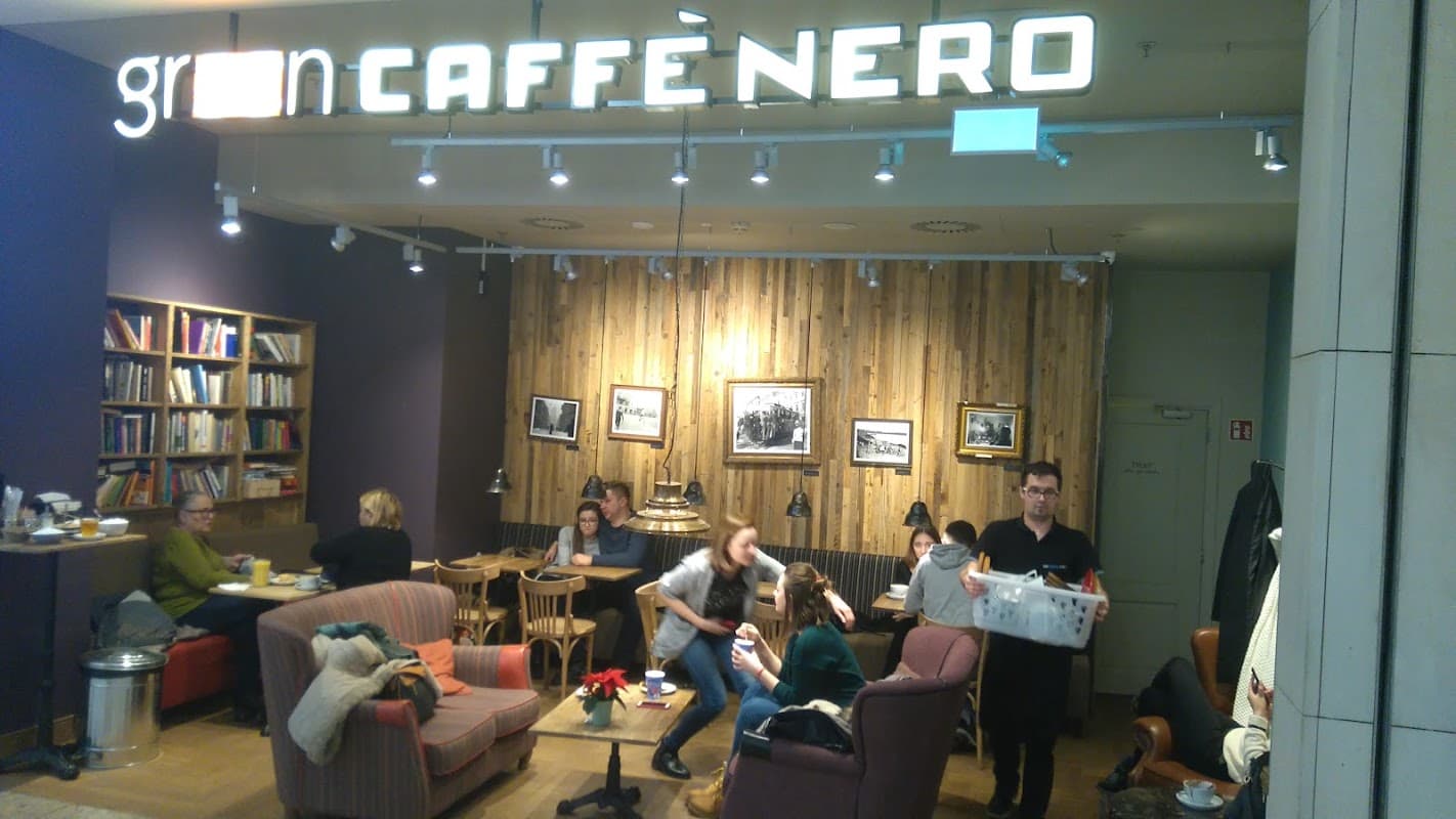 Cozy café interior with wooden accents, patrons enjoying drinks, and a barista serving customers.