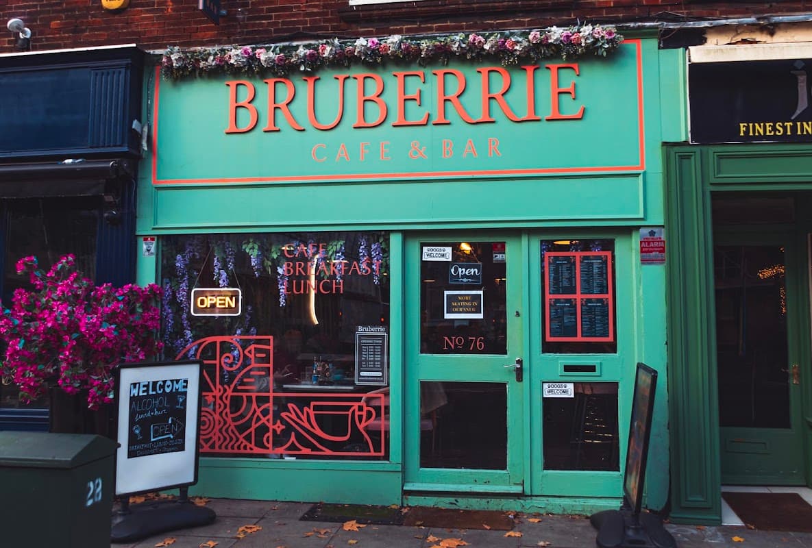 Brightly colored café facade with "Bruberrie Café & Bar" sign, outdoor seating, and floral decorations.