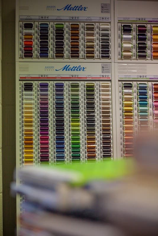 Colorful spools of thread arranged on display, showcasing a variety of hues and shades in a hobby shop setting.