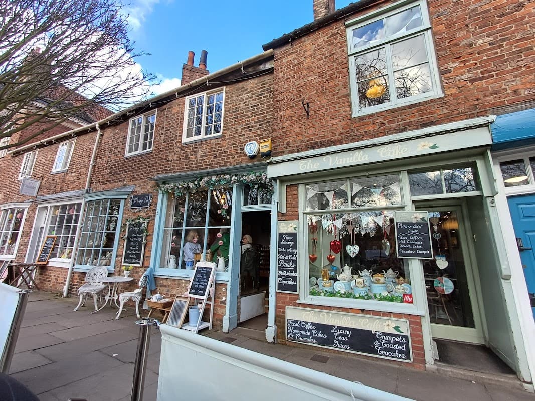 Charming bakery with brick facade, outdoor seating, colorful window displays, and chalkboard menus in York, Yorkshire.