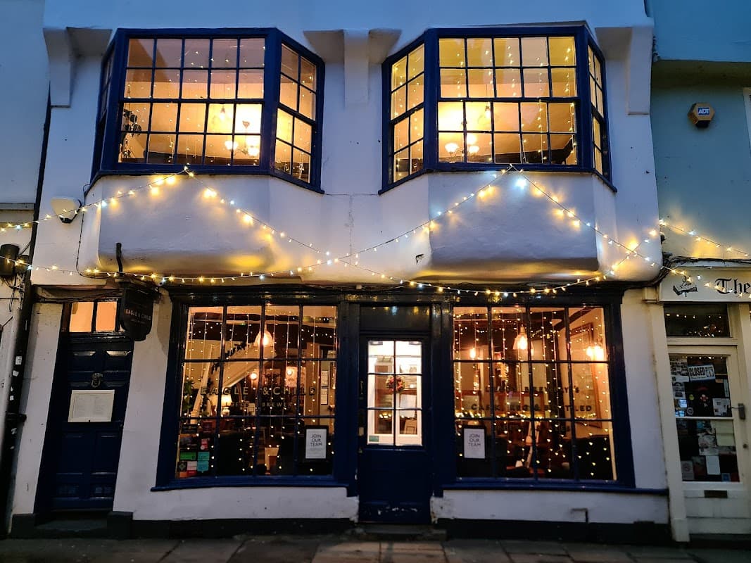 Charming pub exterior with blue window frames, warm lights, and festive string lights adorning the facade.