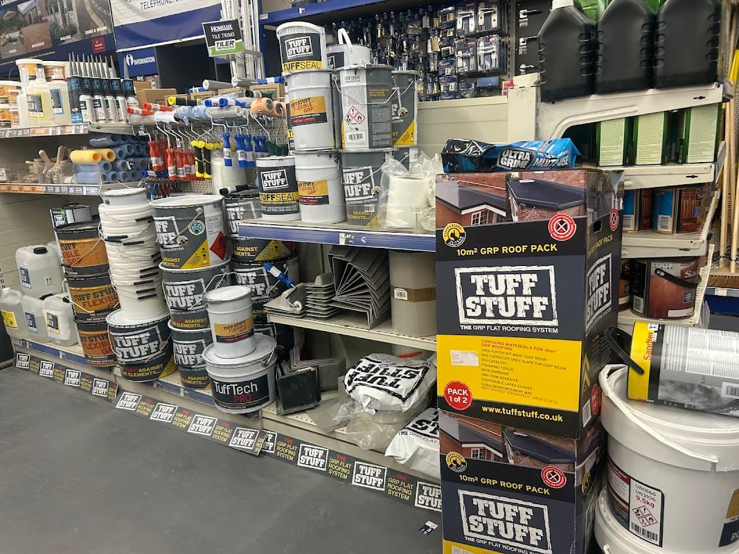 Ironmongers display featuring buckets, tools, roofing materials, and various home improvement supplies on shelves.