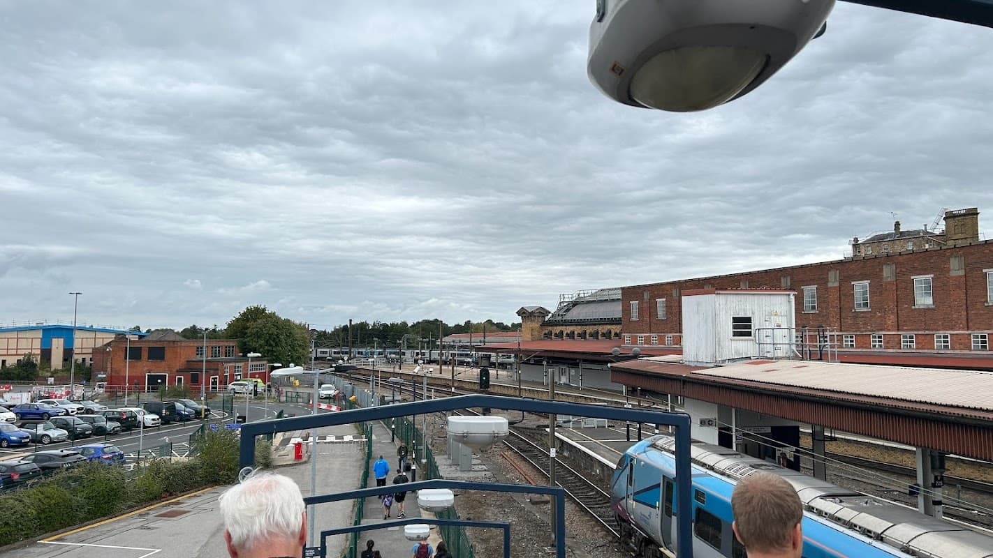 York Commuter Car Park with parked cars, train tracks, and a cloudy sky in the background.