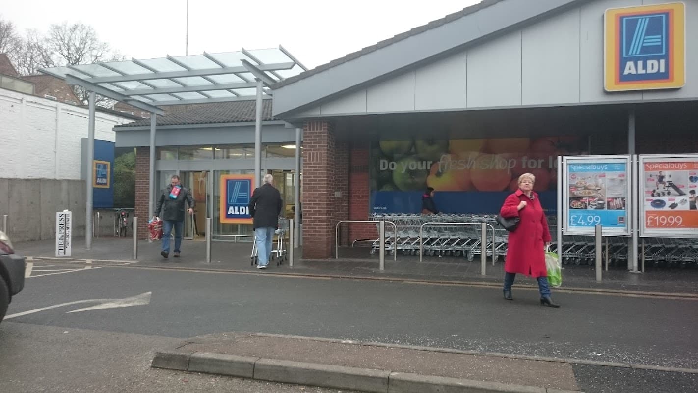 ALDI storefront in York with shoppers, shopping carts, and a colorful promotional sign visible.