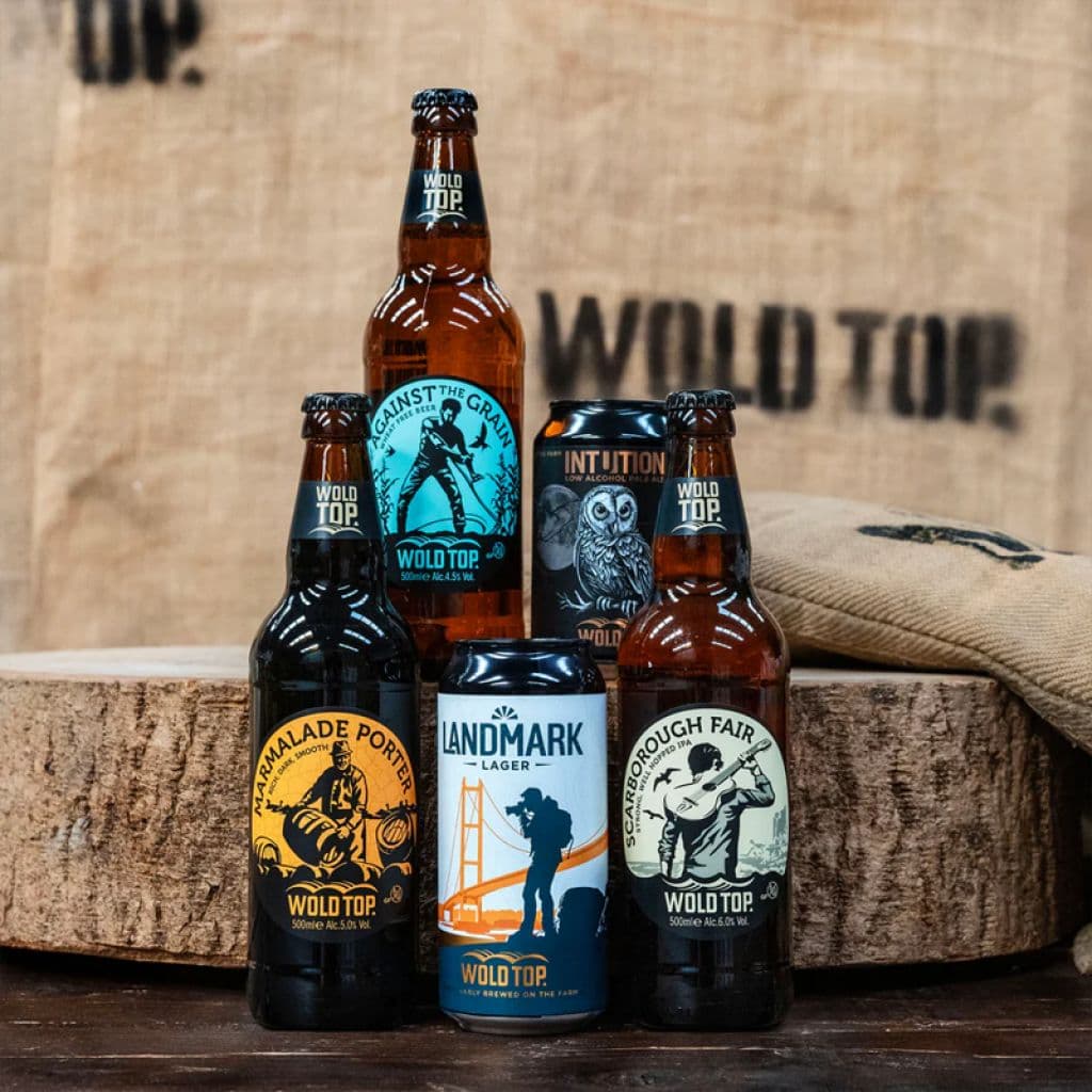 Assorted Wold Top beer bottles and cans on wooden barrel