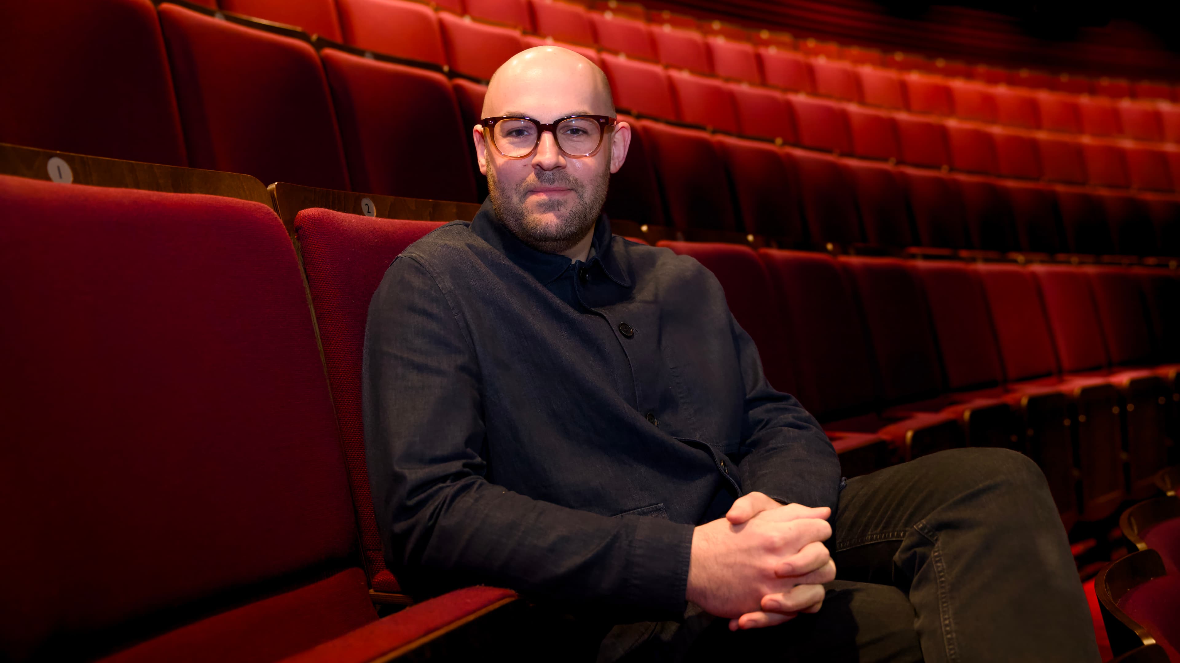 Person seated in an empty theater with red velvet seats
