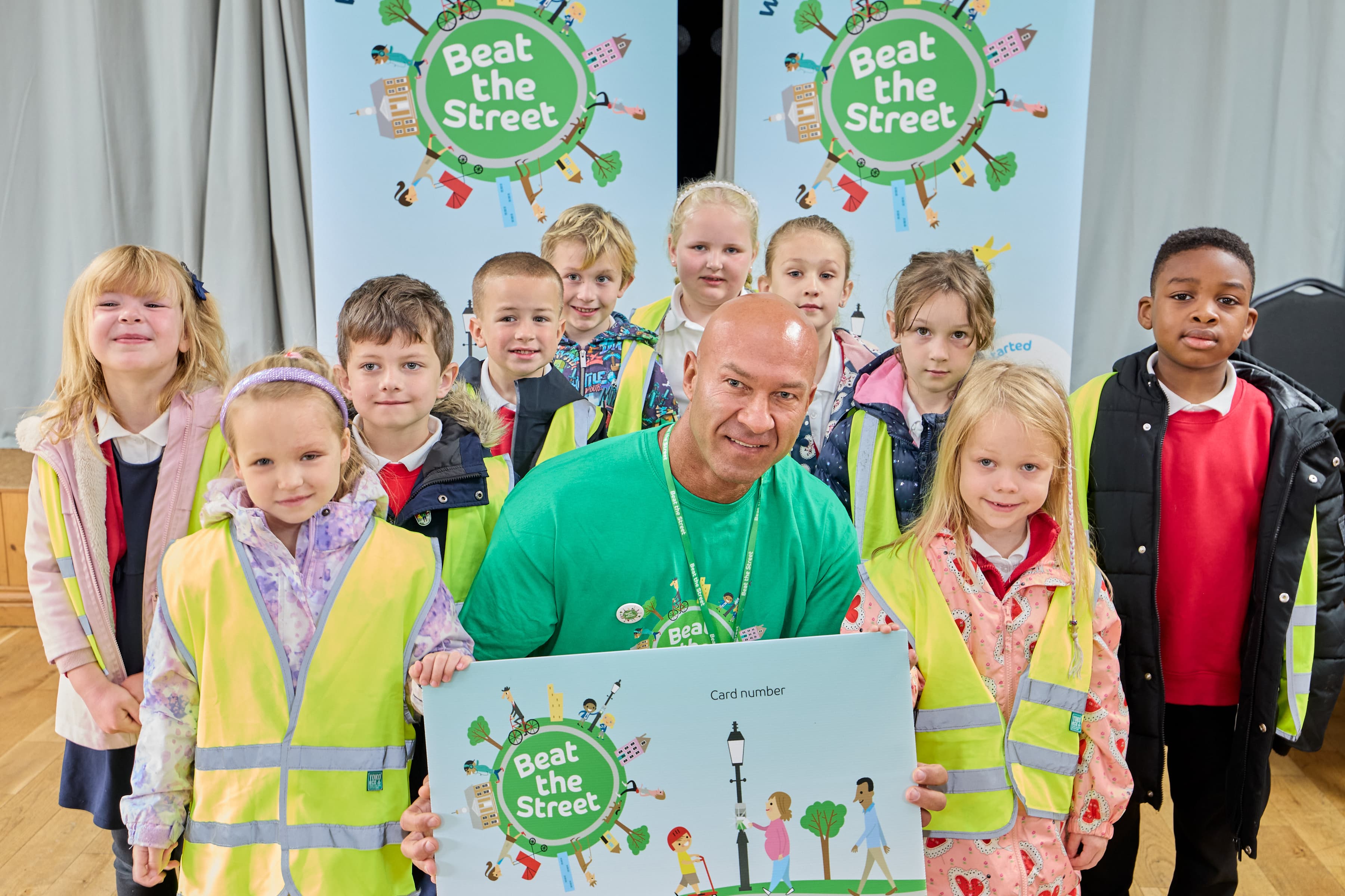Group of children with a man holding Beat the Street sign