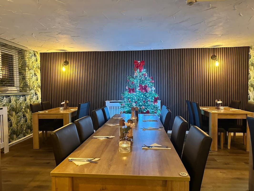 Cozy dining area with wooden tables, black chairs, and a decorated Christmas tree in the corner.