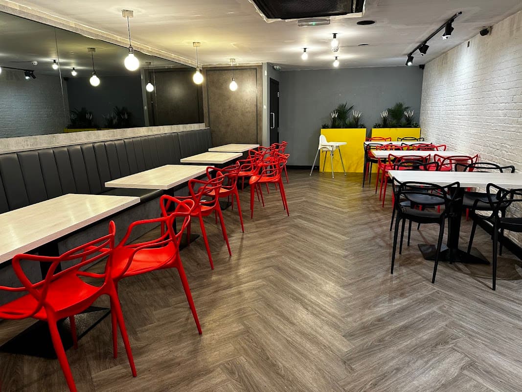 Modern dining area with red and black chairs, wooden tables, and stylish lighting in BrgrBro Batley, Yorkshire.