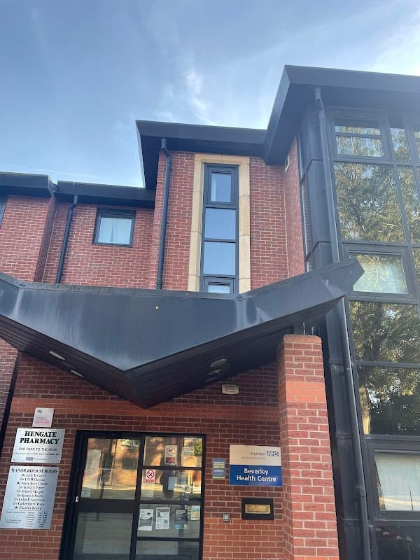 Manor Road Surgery exterior featuring red brick, large windows, and a prominent overhanging roof.
