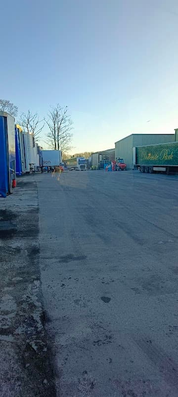 Car park with multiple storage containers and vehicles, set against a clear sky in Cridling Stubbs, Yorkshire.